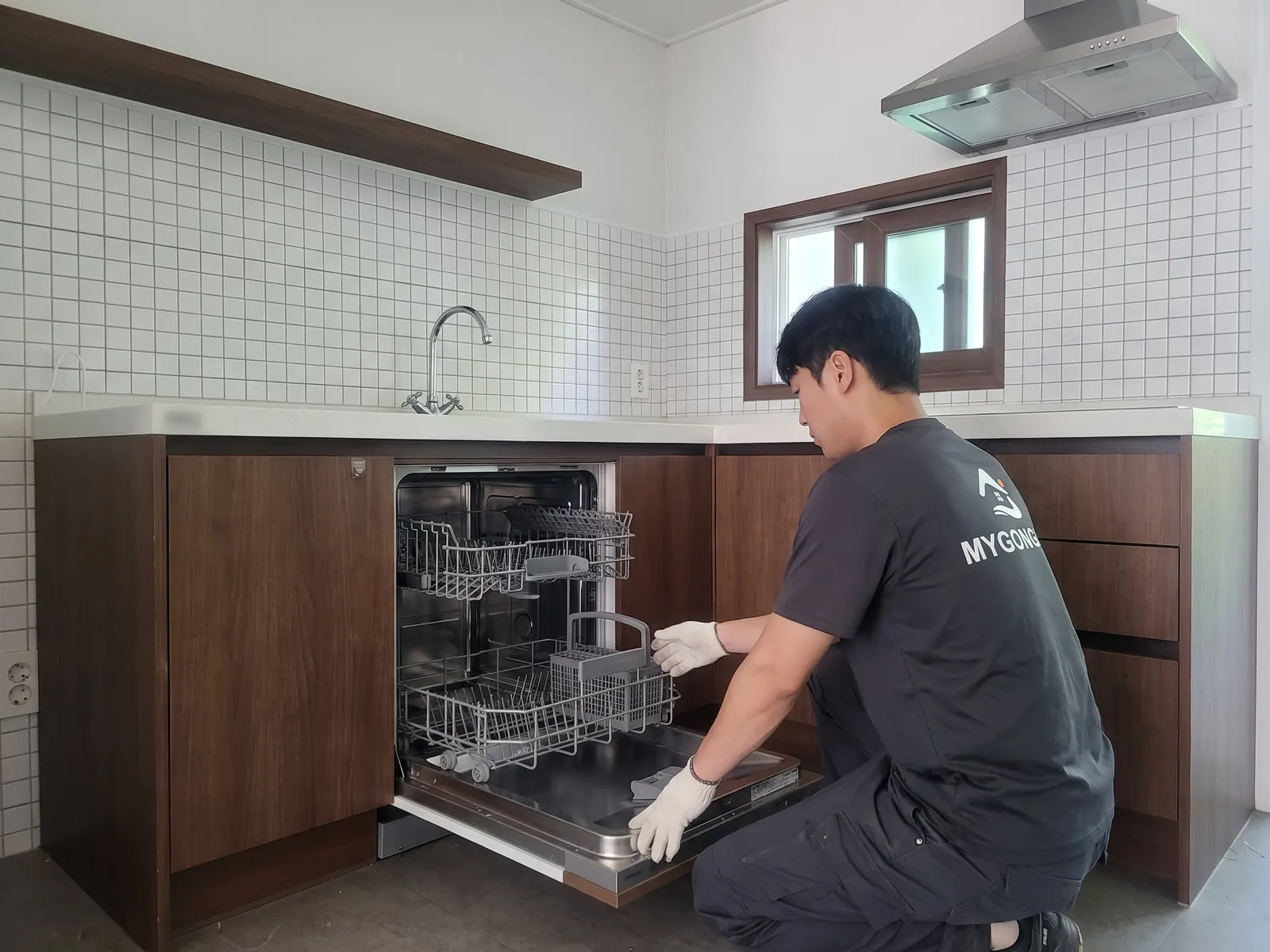 싱크대 하부장에 식기세척기를 넣는 작업자